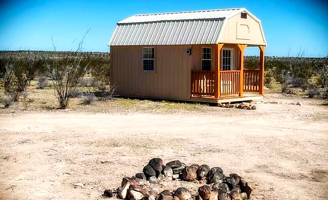 The cabin exterior with a circular stone fire ring on the gravel pad in front