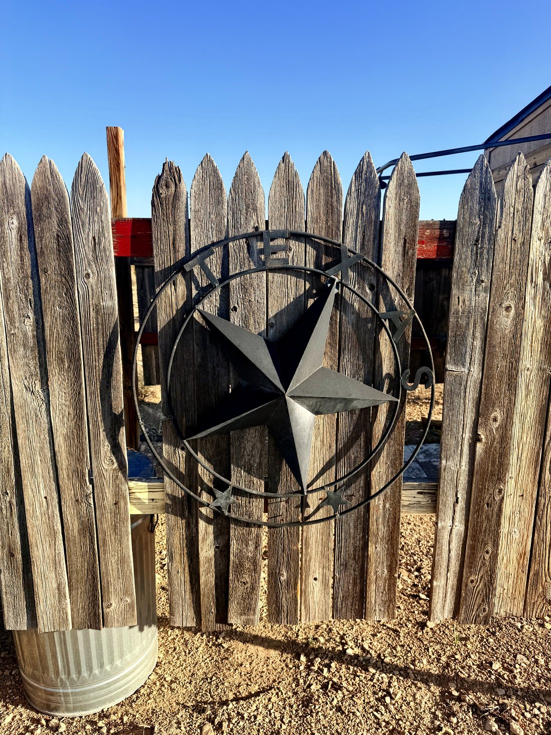 A black metal Texas star mounted on a weathered wooden fence